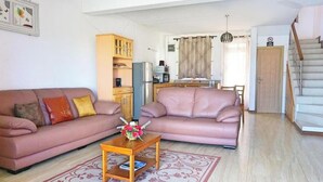 Uma sala de estar com dois sofás, uma mesa de centro, um armário e uma escada.