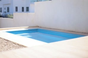 En rektangulär pool med en vit kant, omgiven av en betongplatta.