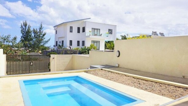 Um edifício moderno com piscina, área cercada e céu claro.