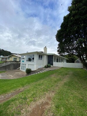 A residential house with a front yard, a driveway, and a white fence.
