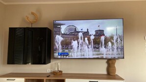Een flatscreen televisie bevestigd aan een muur, waarop een stadsbeeld met een fontein te zien is.