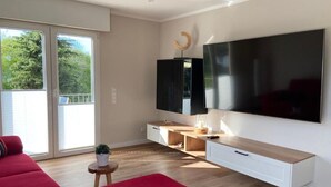 Een moderne woonkamer met een grote flatscreen televisie, een rode bank en een houten salontafel.