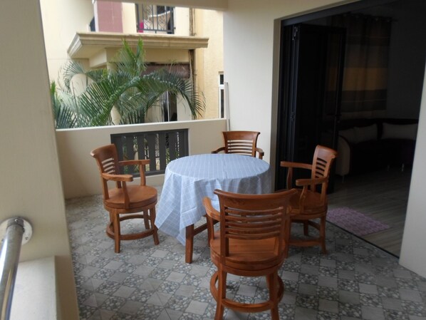 Un balcon avec une table et des chaises, un sol carrelé et une vue sur un immeuble doté d’un balcon.