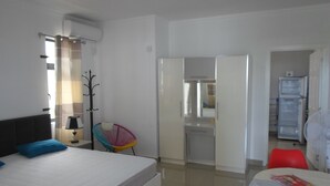 A hotel room with a bed, a chair, a table, a wardrobe, and a mirror. - Residence La Colombe Vacation Rentals (Mont Choisy)