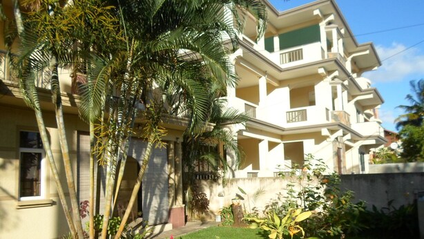 A multi-story residential building with balconies, surrounded by lush greenery and a well-maintained lawn. - Residence La Colombe Vacation Rentals (Mont Choisy)