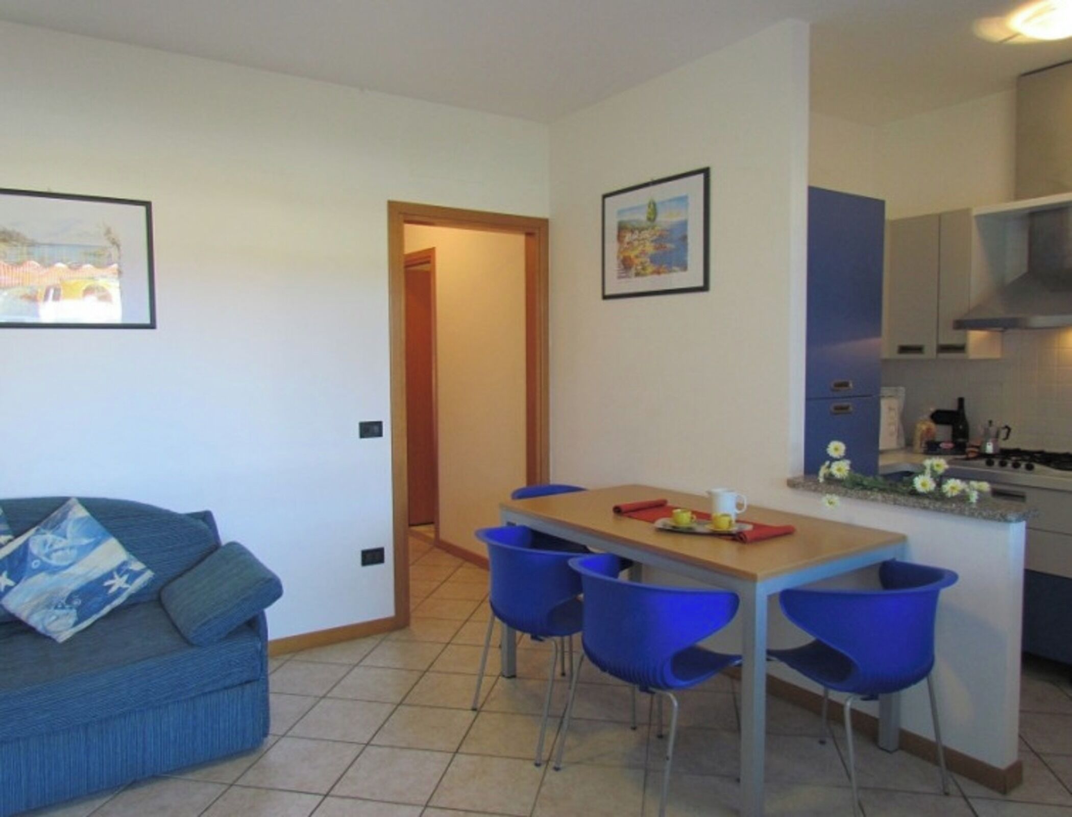 A compact living space with a dining area, kitchenette, and a sofa with blue cushions.