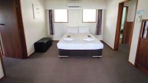 Habitación de hotel con cama, maleta, aire acondicionado y ventana con cortinas.