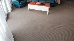 Una sala de estar con un sofá, sillones, una mesa de centro y un cuadro enmarcado en la pared.