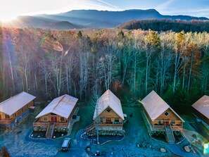 A model of a cabin-style resort with multiple buildings, a clear driveway, and a surrounding forest.
