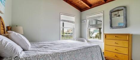 Un dormitorio con una cama, un aparador de madera, un ventilador de techo y una ventana con persianas.