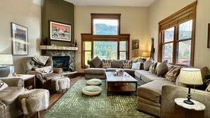 A cozy living room with a fireplace, comfortable seating, and large windows offering a view of the outdoors. - 2348 Red Hawk Townhomes 3 Bedroom Condo by RedAwning (Keystone)