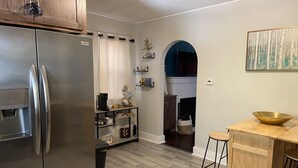 Een moderne keuken met een roestvrijstalen koelkast, houten kastjes, een koffiehoek en een houten kookeiland met barkrukken.