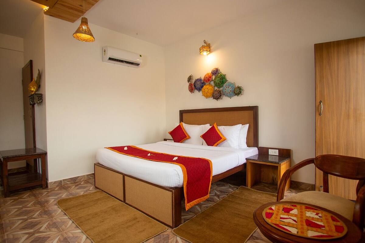 Habitación de hotel ordenada con cama, mesitas de noche, una silla y un adorno en la pared.