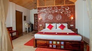 Un dormitorio con techo de madera, una cama con ropa de cama roja y blanca, una mesita de noche, un aparador y una pared con azulejos decorativos.
