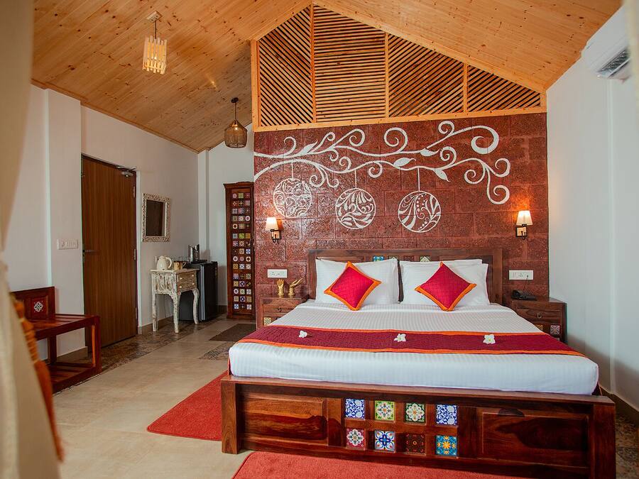 Un dormitorio con techo de madera, una cama con ropa de cama roja y blanca, una mesita de noche, un aparador y una pared con azulejos decorativos.