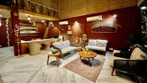 Un vestíbulo amplio con mostrador de recepción, zona de estar y una pared decorativa.