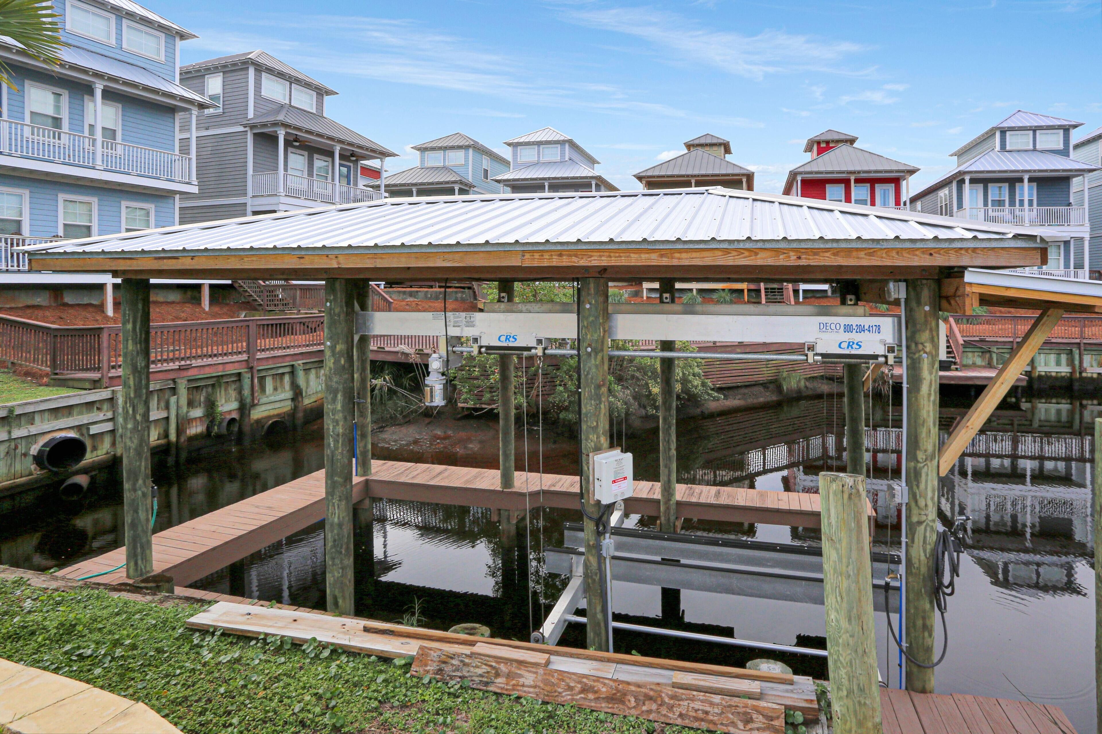 A waterfront dock with a covered seating area, wooden walkways, and a water channel.