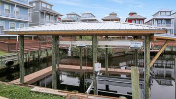 A waterfront dock with a covered seating area, wooden walkways, and a water channel.