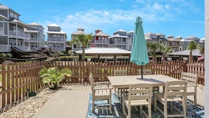 A patio area with a table and chairs, a wooden fence, and a view of colorful houses in the background. - The Ricks Carlton (Port St. Joe)