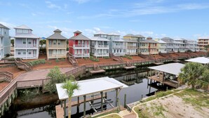 A row of waterfront houses with docks, a small docked boat, and a clear sky. - The Ricks Carlton (Port St. Joe)