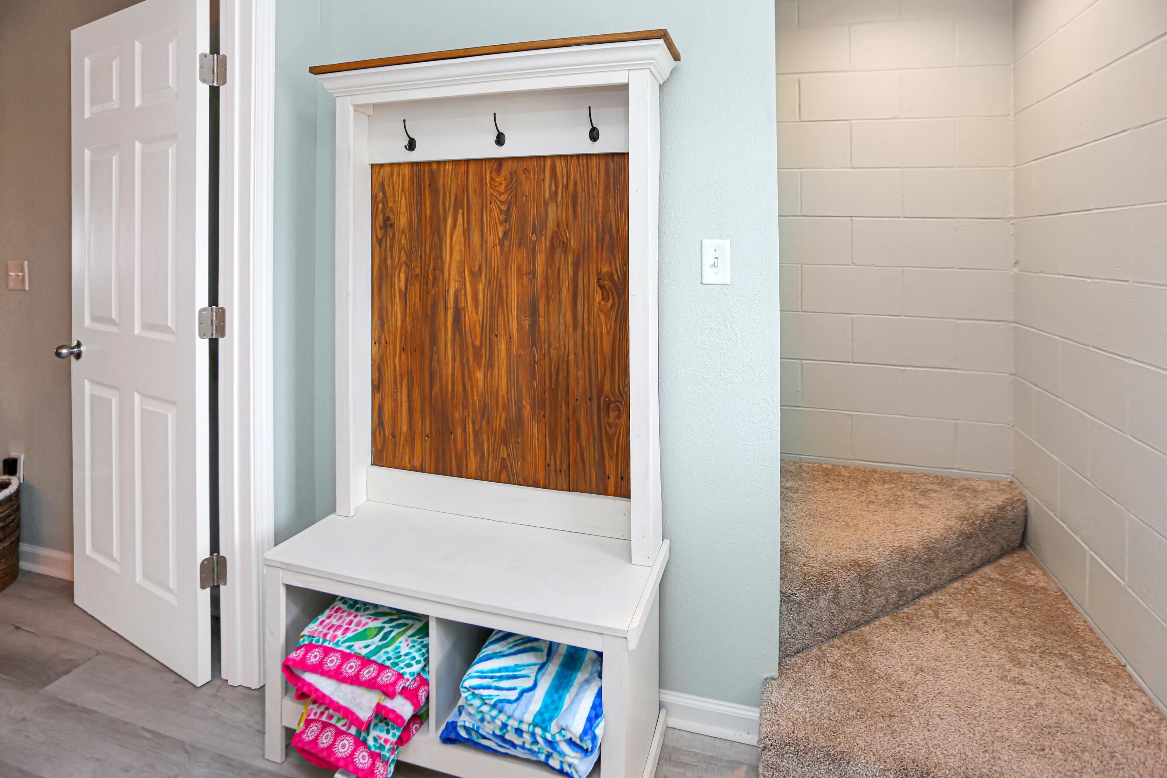 A hallway with a white bench, a wooden panel, and a carpeted staircase.
