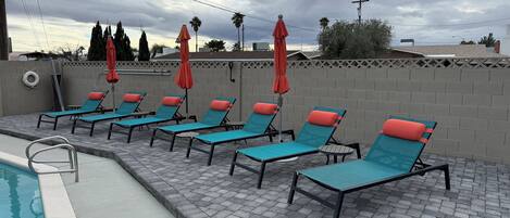 A poolside area with lounge chairs and umbrellas.