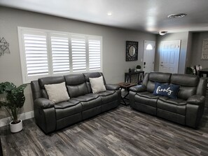A living room with two leather sofas, a coffee table, and a potted plant.