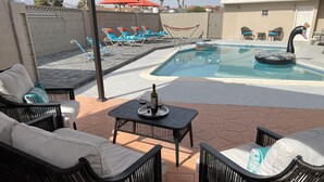 Un espace piscine avec des chaises longues, une table avec une bouteille et des verres, et un flotteur en forme de cygne.
