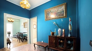 A room with a blue wall, a wooden cabinet with decorative items, a bench, and a dining area with chairs and a table. - Acropolis view vintage style apartment (Athens)
