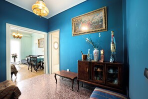 A room with a blue wall, a wooden cabinet with decorative items, a bench, and a dining area with chairs and a table. - Acropolis view vintage style apartment (Athens)