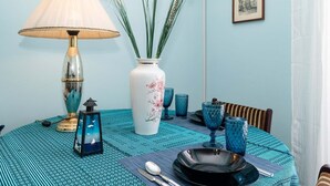 A dining table set with a vase of flowers, a lamp, and blue glassware. - Acropolis view vintage style apartment (Athens)