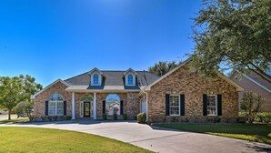 A two-story brick house with a front porch, a driveway, and a well-maintained lawn.