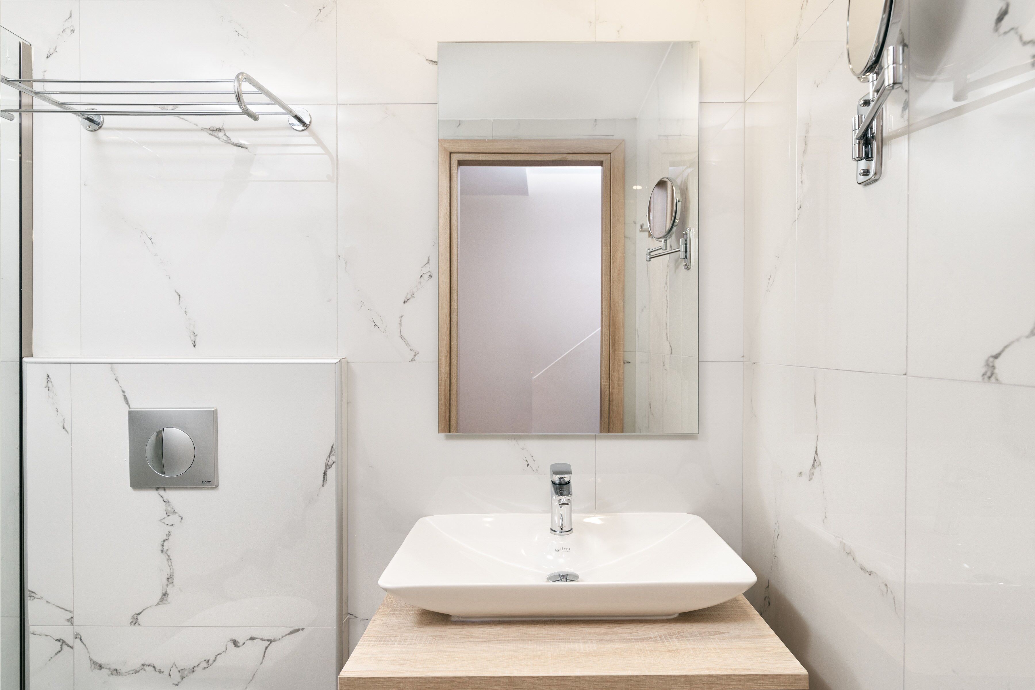 Un baño moderno con un lavabo de mármol blanco, una cabina de ducha de cristal y un perchero para toallas.