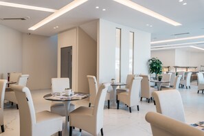 Un moderno vestíbulo de hotel con mobiliario blanco, una mesa de centro de vidrio y una planta en maceta.