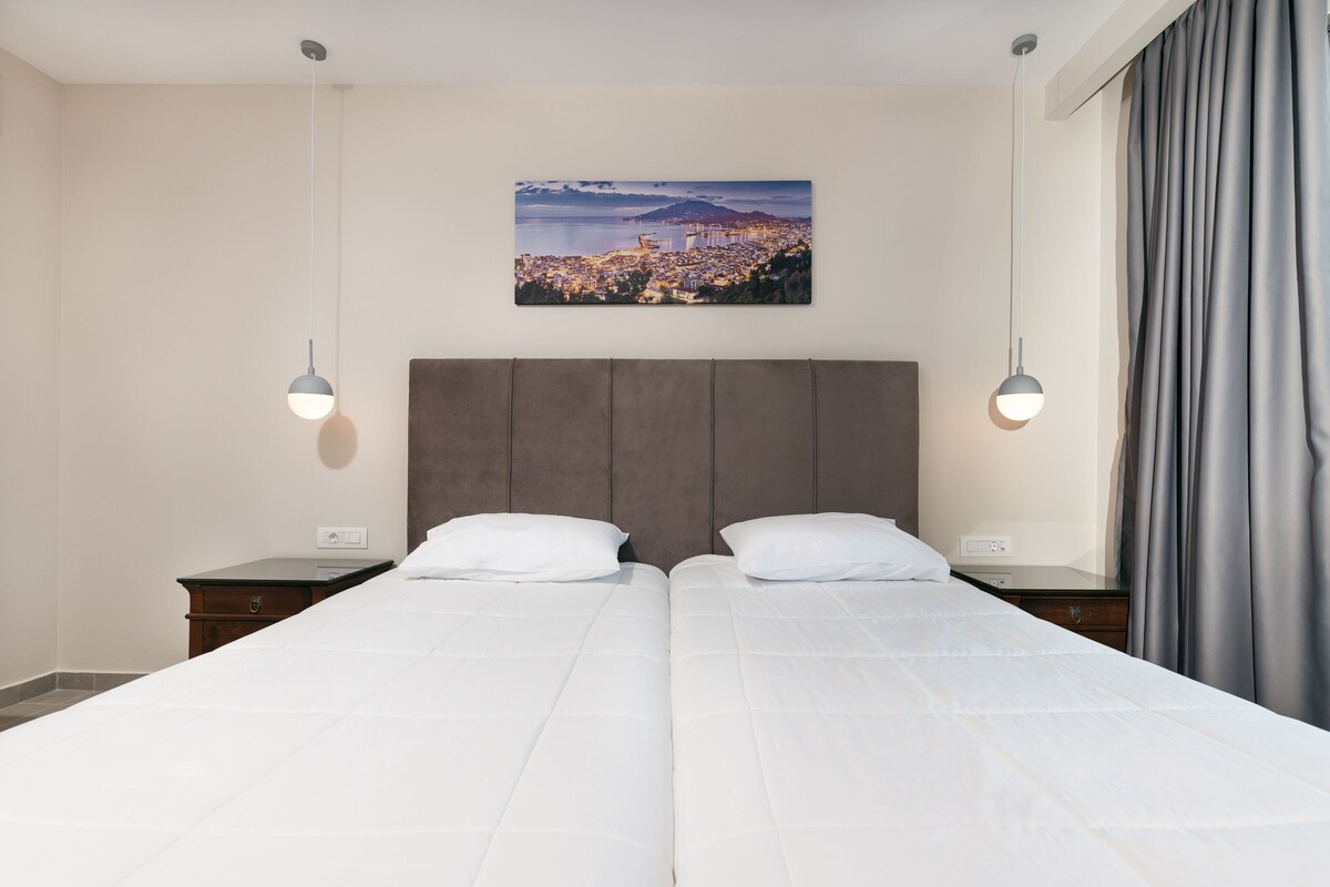 Habitación de hotel con dos camas, vistas a la ciudad y un ventanal con cortinas.