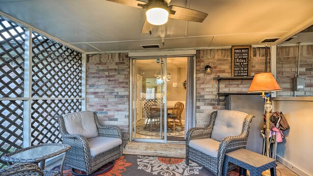 Un'area patio accogliente con mobili in vimini, una ventola a soffitto e un muro in mattoni.