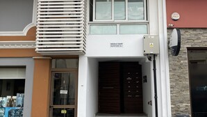 Een gebouw met een bord waarop 'VASSILLO COURT' staat en een duidelijke ingang met een paar dubbele deuren.