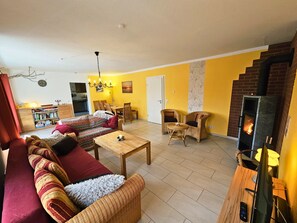 A living room with a sofa, chairs, a table, a fireplace, and a television.