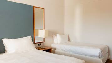 A hotel room with two beds, a nightstand, a lamp, and a mirror.