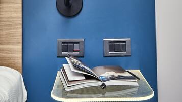 A modern room with a blue accent wall, a black floor lamp, and a small table with books and a pen.