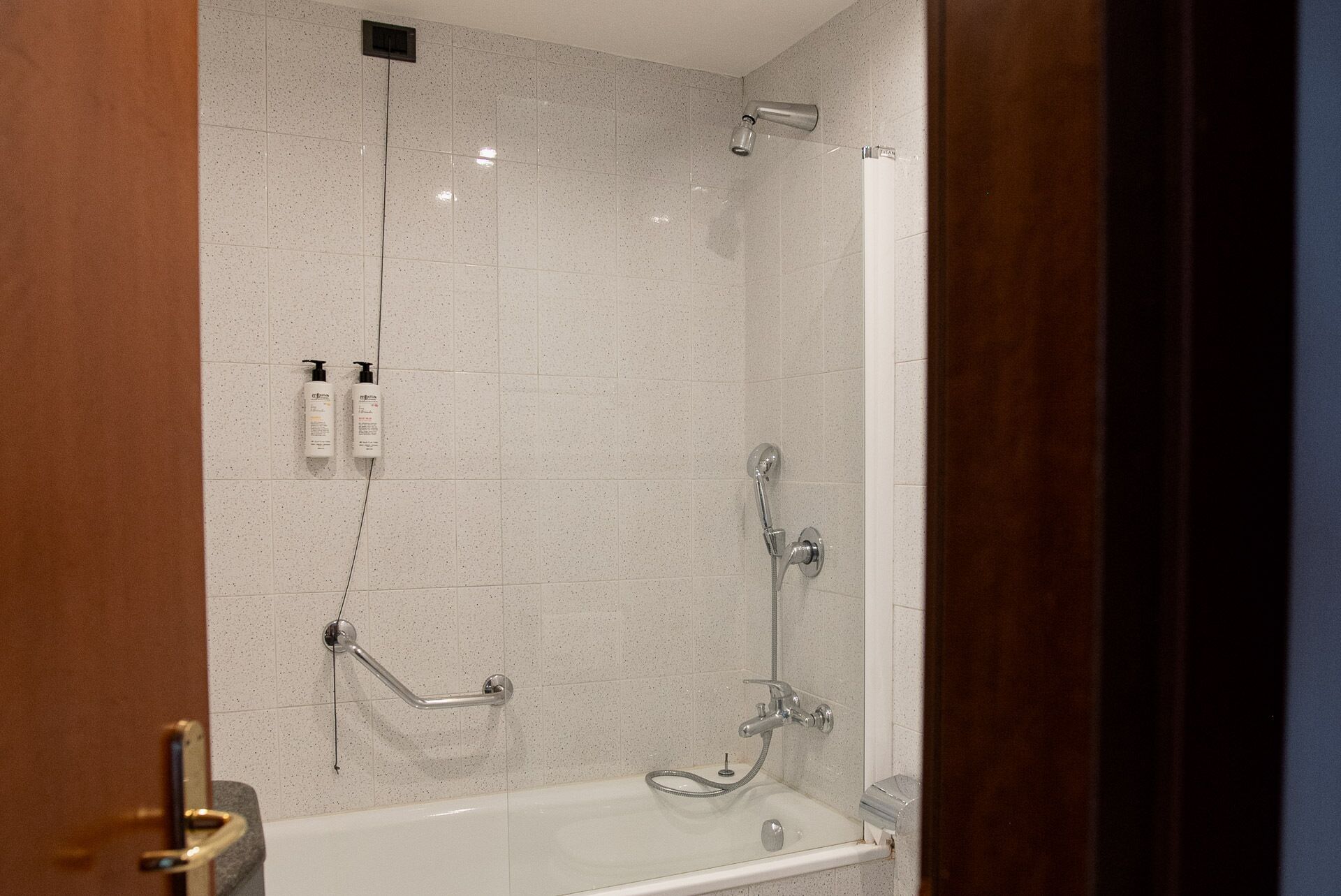 Un baño moderno con bañera, ducha y barras de apoyo.