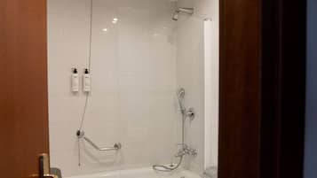 Un baño moderno con bañera, ducha y barras de apoyo.
