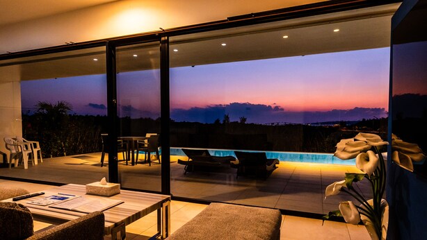 Un área de estar moderna al aire libre con piscina, sillones cómodos y vistas al atardecer.