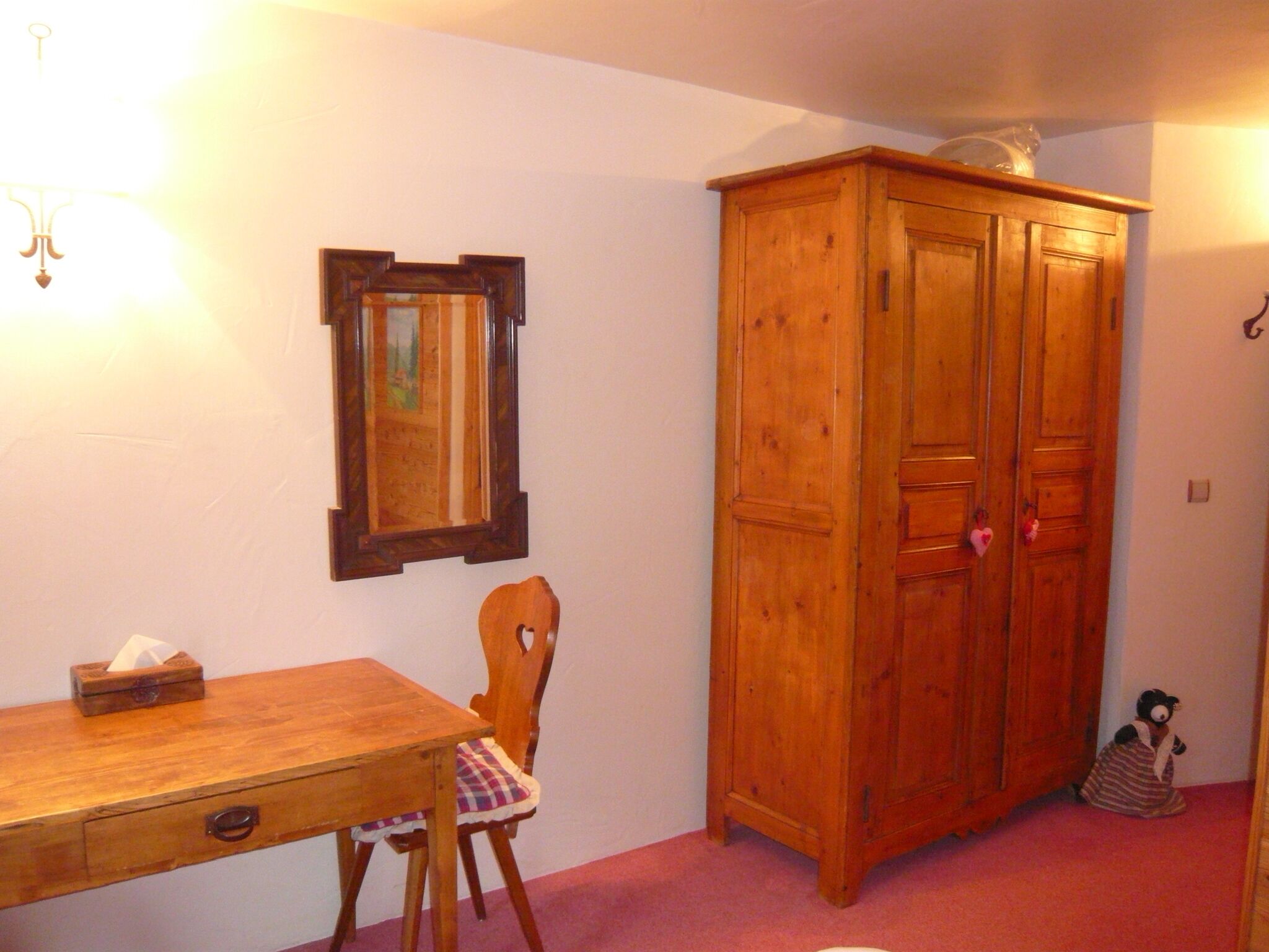 Un mueble de madera, una silla de madera, una mesa de madera y un espejo en la pared.