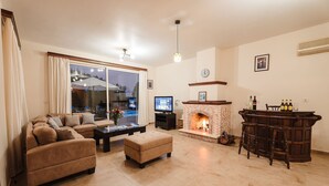 Ein Wohnzimmer mit Kamin, Fernseher und einer Bar.