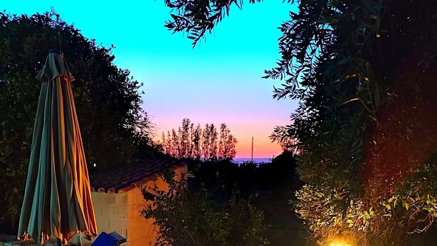 Eine Terrasse mit Lounge-Möbeln, einem Tisch, einer Steinmauer und einer Laterne.
