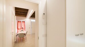 A hallway leading to a room with a wooden ceiling, a white door, and a table with chairs.