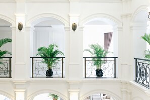Stunning interior space with elegant white columns and arches, featuring balconies with potted plants and wrought iron railings.