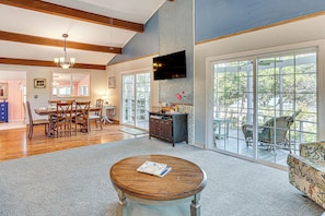 A spacious living room with a dining area, large windows, and a fireplace.