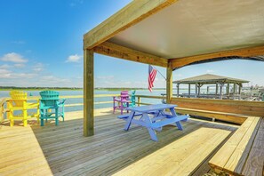 A wooden deck with picnic tables and colorful Adirondack chairs overlooking a body of water. - 'Reel Blessed' Topsail Beach Home w/ Private Dock! (Topsail Beach)